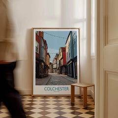 Colchester England travel poster framed on floor in bright room, man walking past