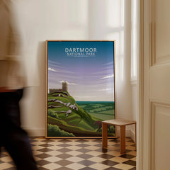 Framed Dartmoor National Park travel poster on floor in bright hallway, person walking past