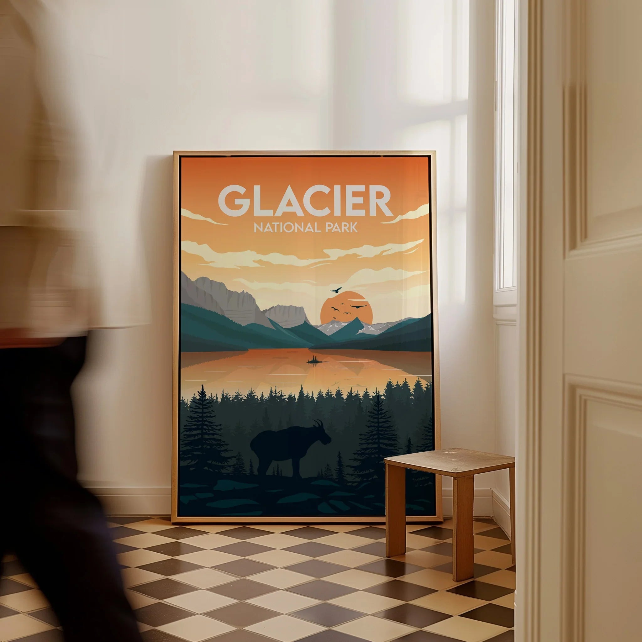 Framed Glacier National Park travel poster with sunset landscape on floor, man walking past