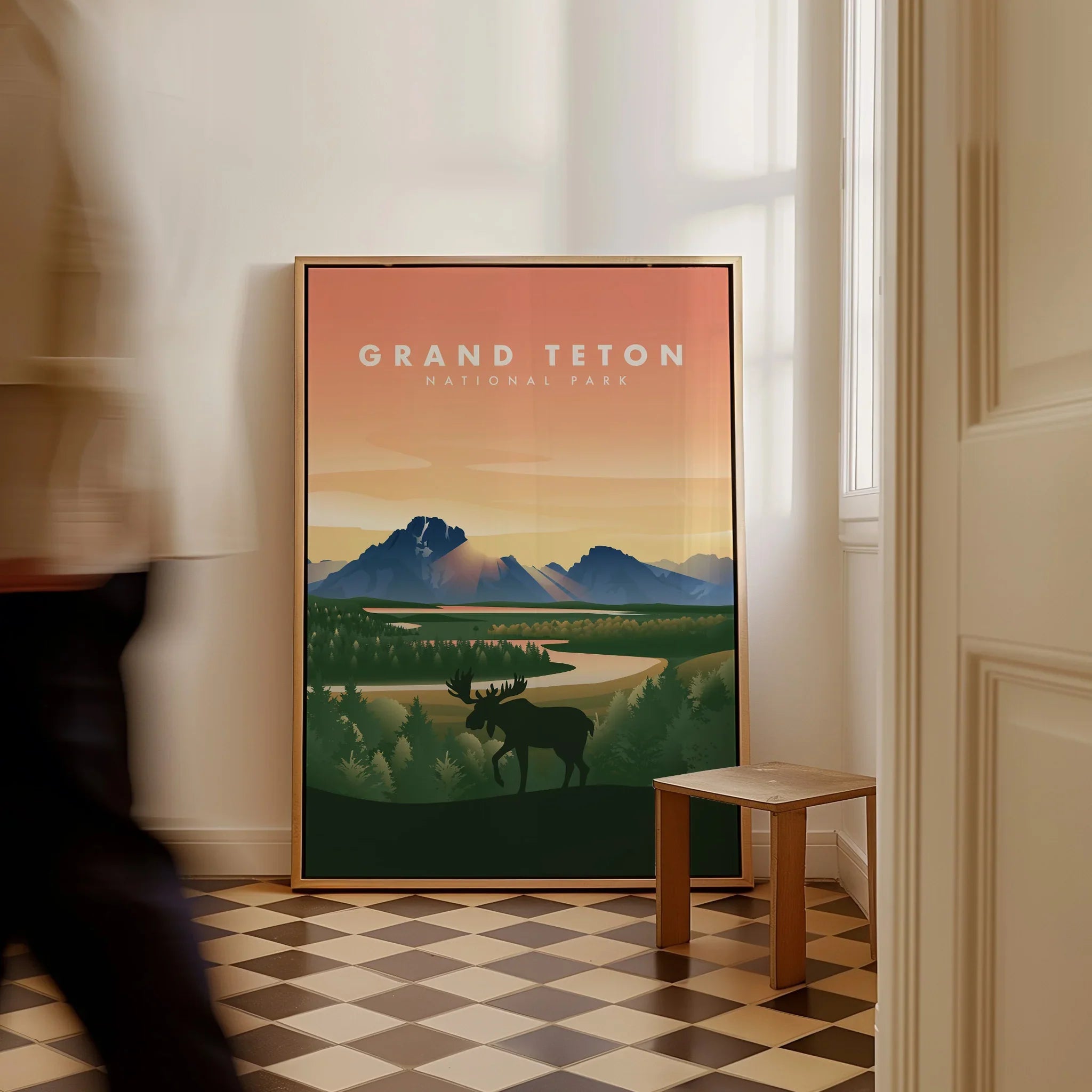 Framed Grand Teton National Park poster with moose and mountains, resting on floor indoors