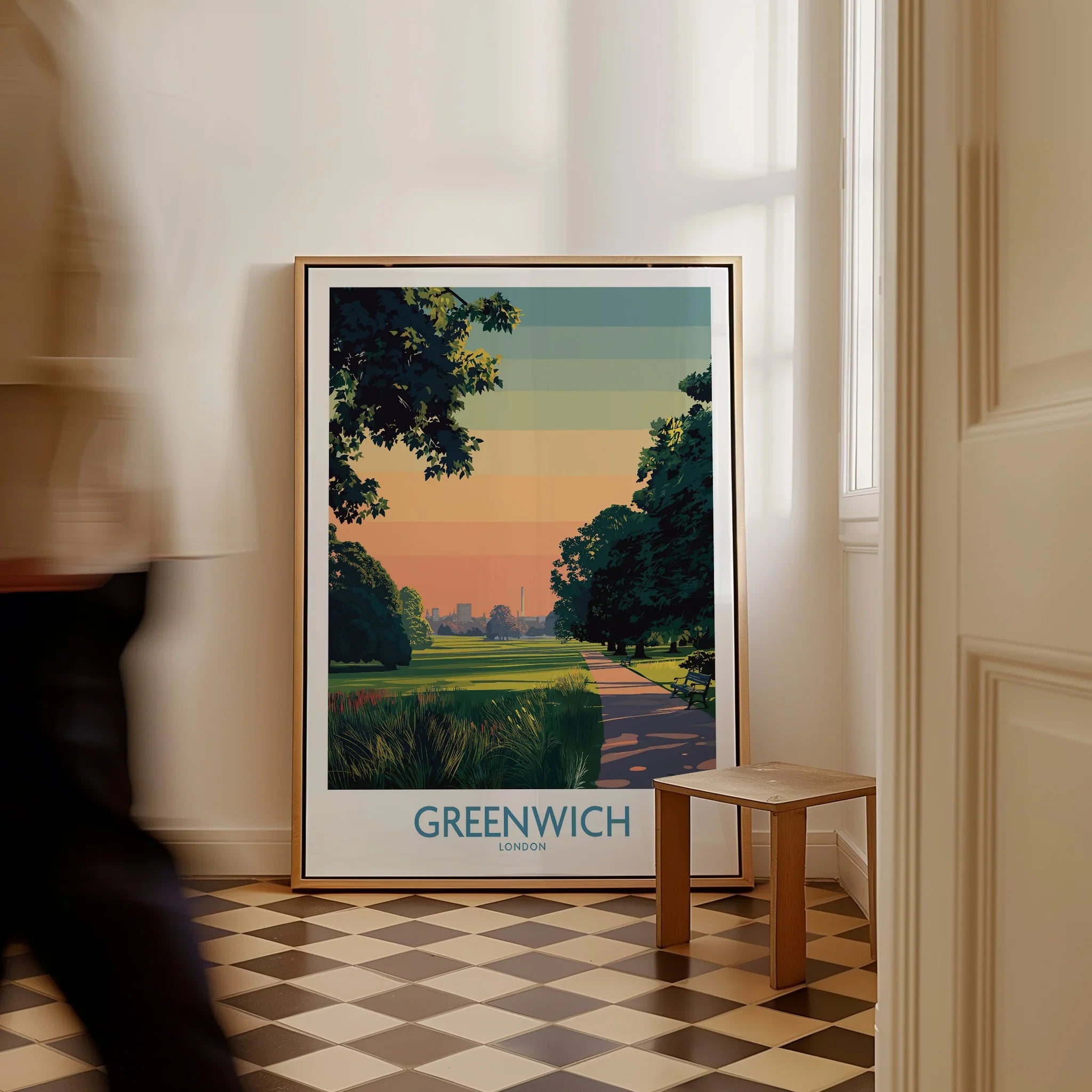 Framed Greenwich London travel poster on floor in bright entryway, man walking past.