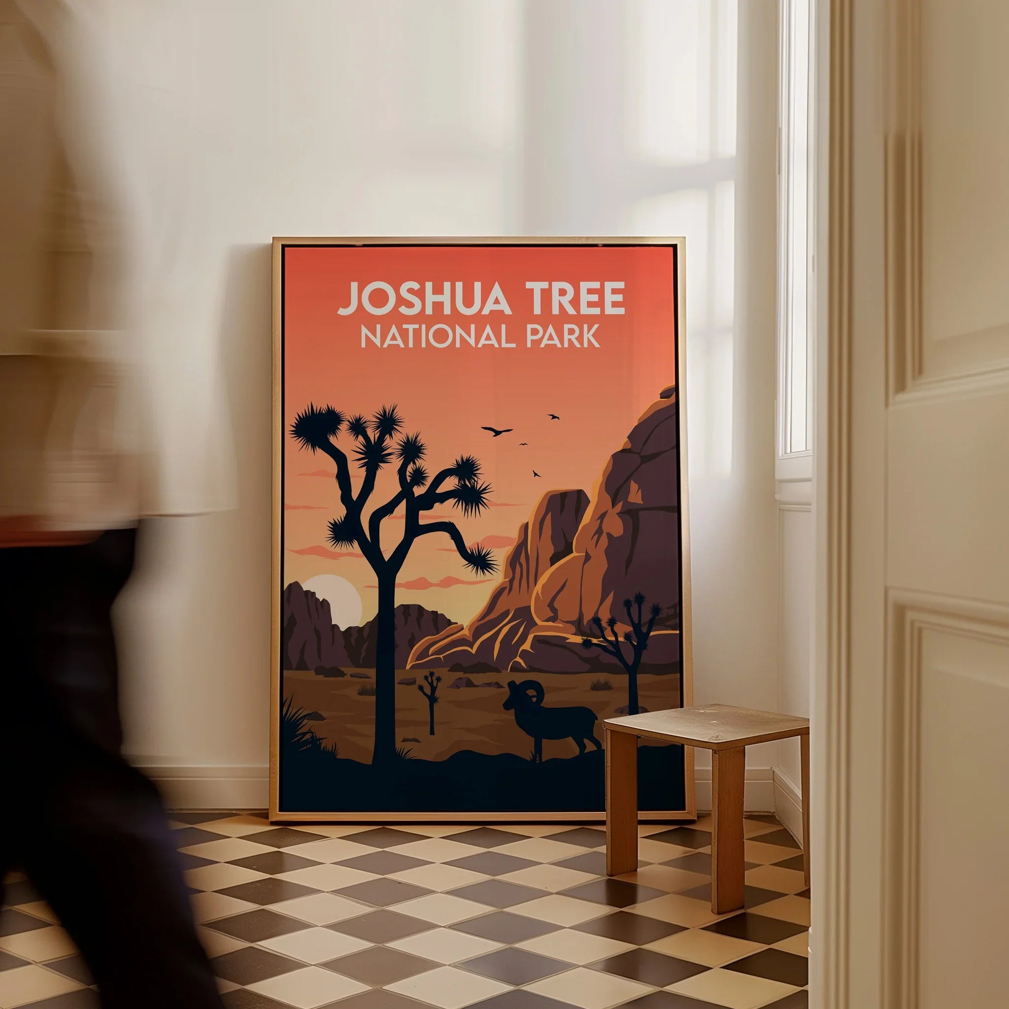 Framed Joshua Tree National Park travel poster on floor in sunlit room, person walking by