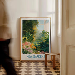 Framed Kew Gardens travel poster with vibrant botanical art on a checkered floor, man walking by.