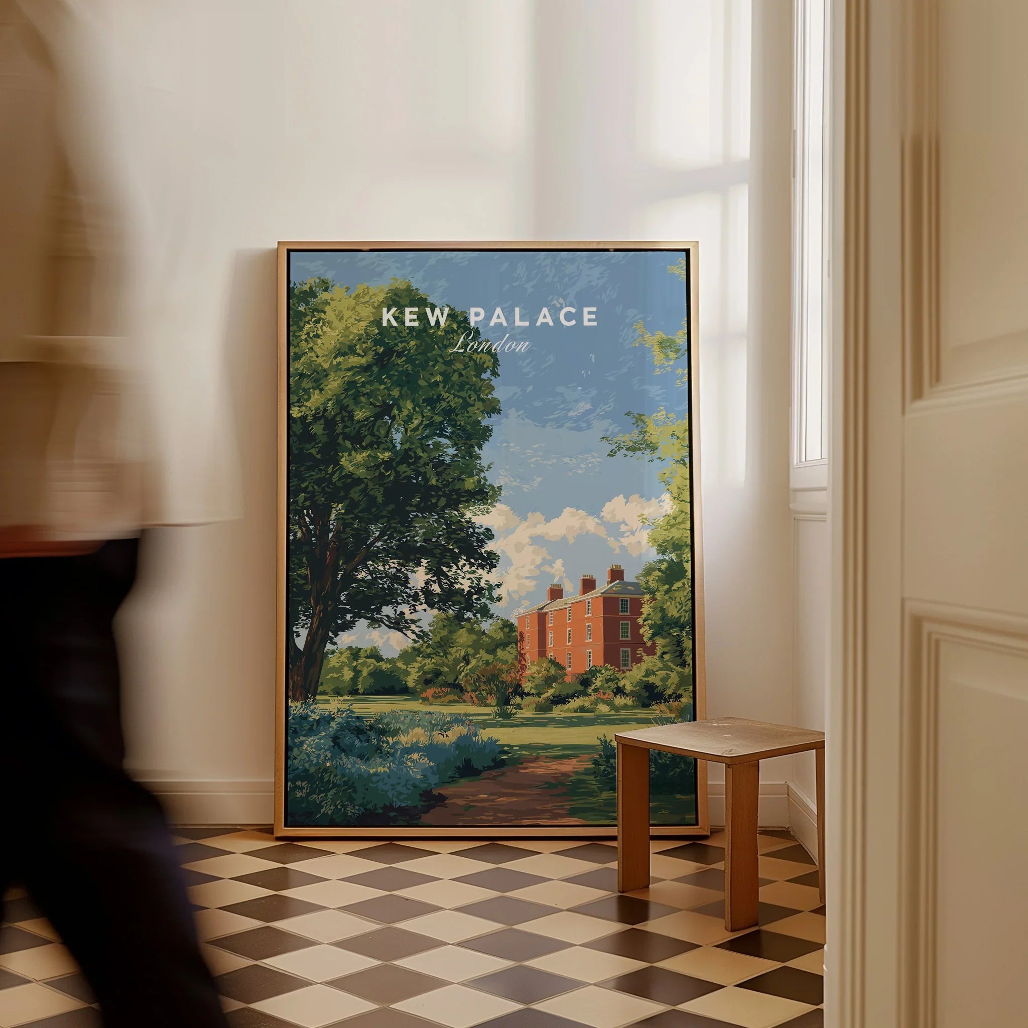 Framed Kew Palace London travel poster on floor in bright hallway, man walking past.