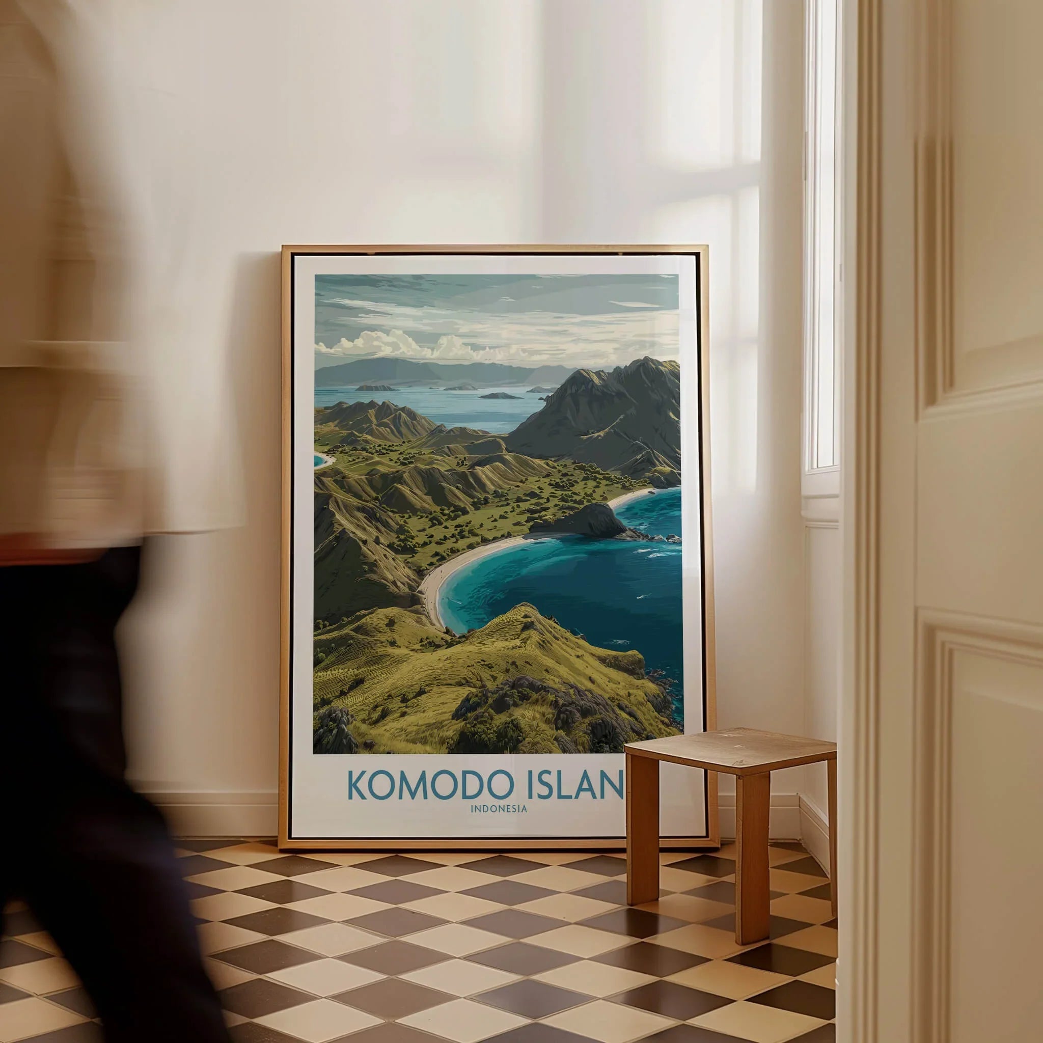 Framed Komodo Island travel poster leaning on wall in bright hallway with checkerboard floor.
