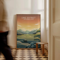 Framed Lake District National Park travel poster on floor in sunlit hallway, man walking by.