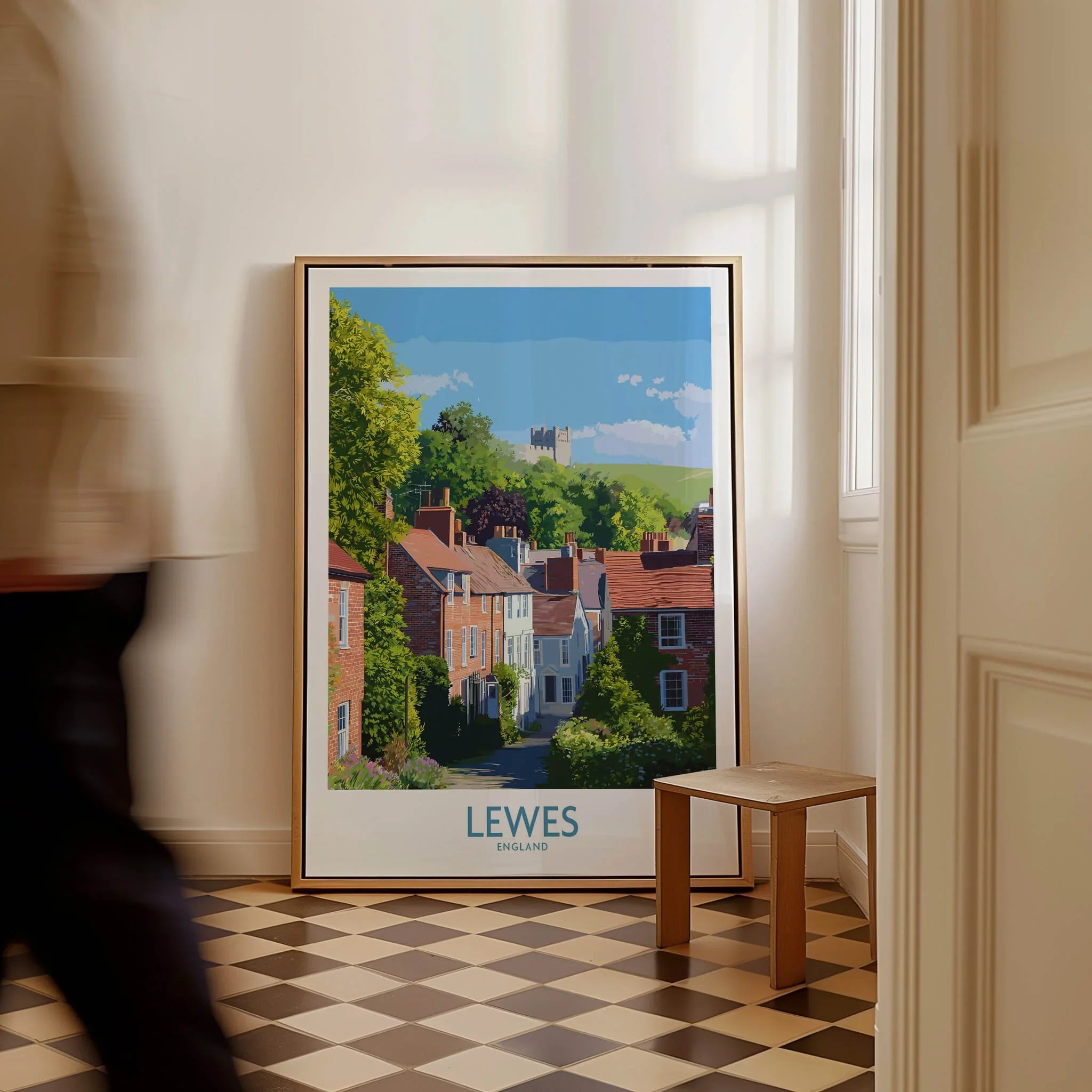 Framed Lewes England city travel poster on floor with man walking past and checkered tile
