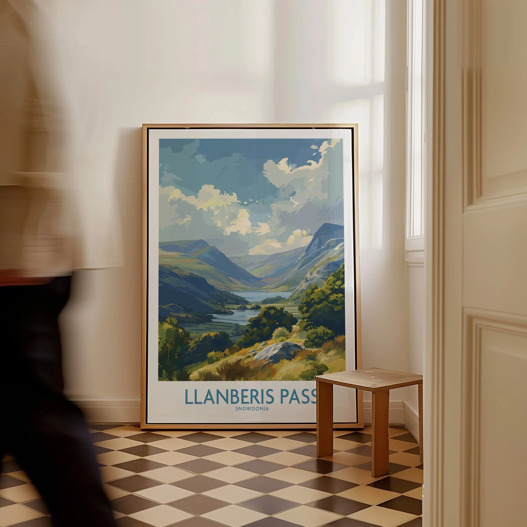 Framed Llanberis Pass Snowdonia travel poster leaning on wall, man walking past