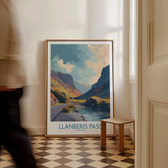 Framed Llanberis Pass travel poster on checkered floor in bright hallway, man walking by