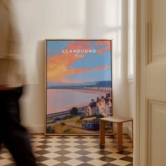 Framed Llandudno Wales travel poster with colorful sunset skyline resting on floor