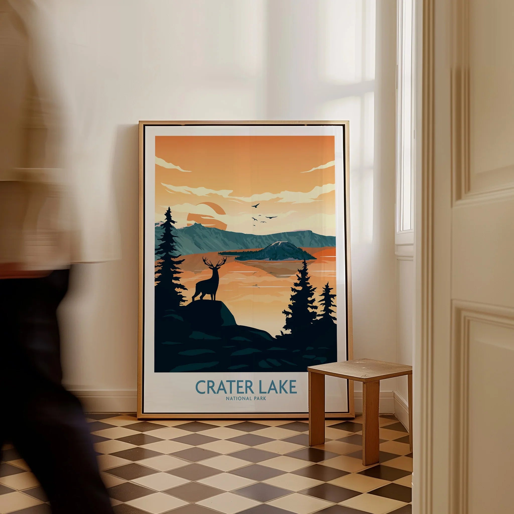 Framed Crater Lake National Park art print on floor, with silhouette deer and mountain scenery.