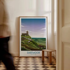 Framed Dartmoor National Park poster with landscape art, leaning on wall, person walking by