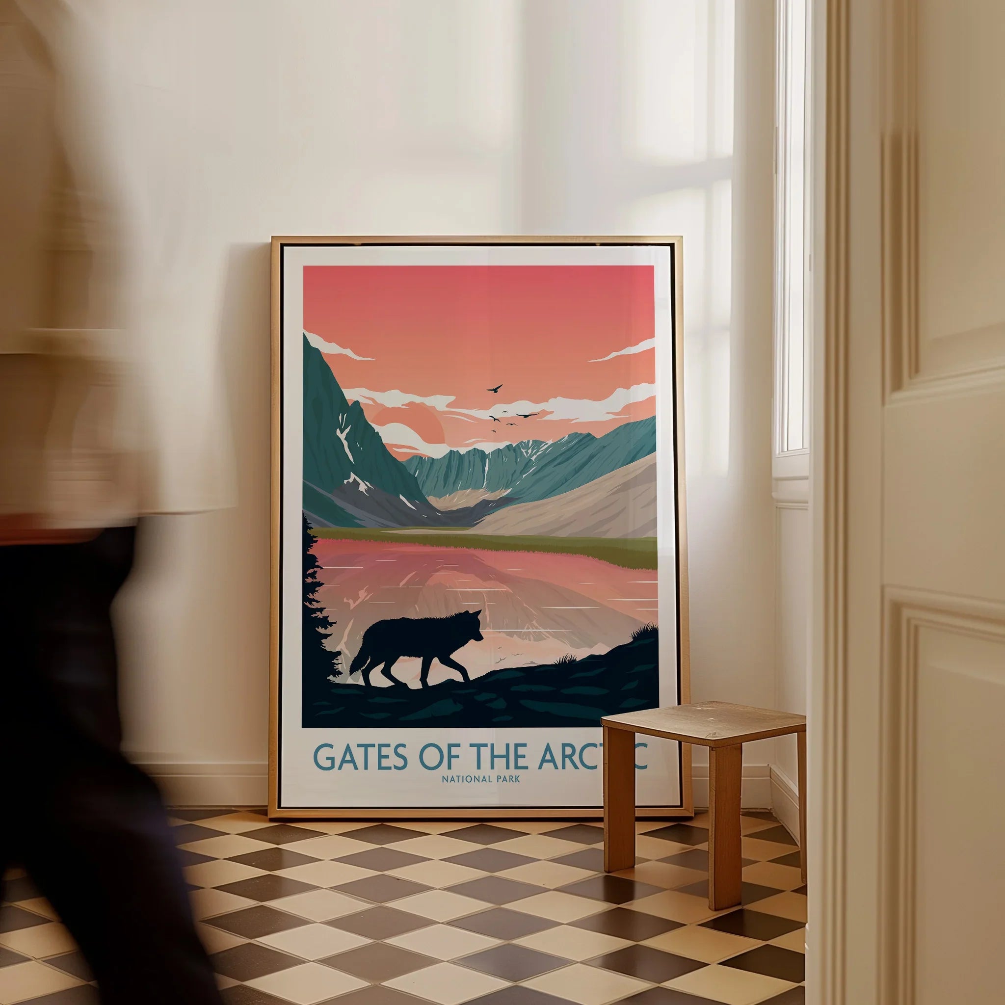 Framed Gates of the Arctic National Park print with wolf silhouette, mountains, and sunset on floor in modern hallway.