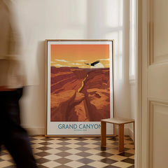 Framed Grand Canyon National Park travel poster on floor in sunlit room, man walking past.