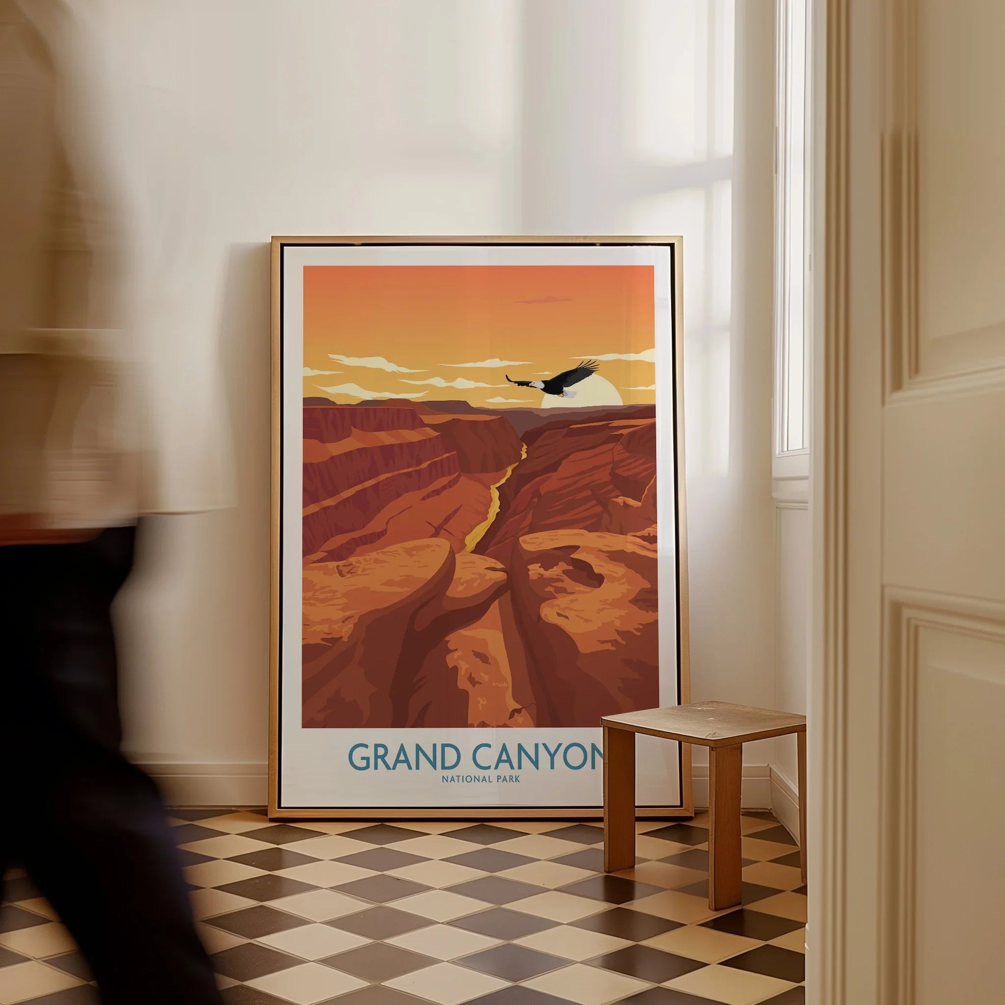 Framed Grand Canyon National Park travel poster on floor in sunlit room, man walking past.