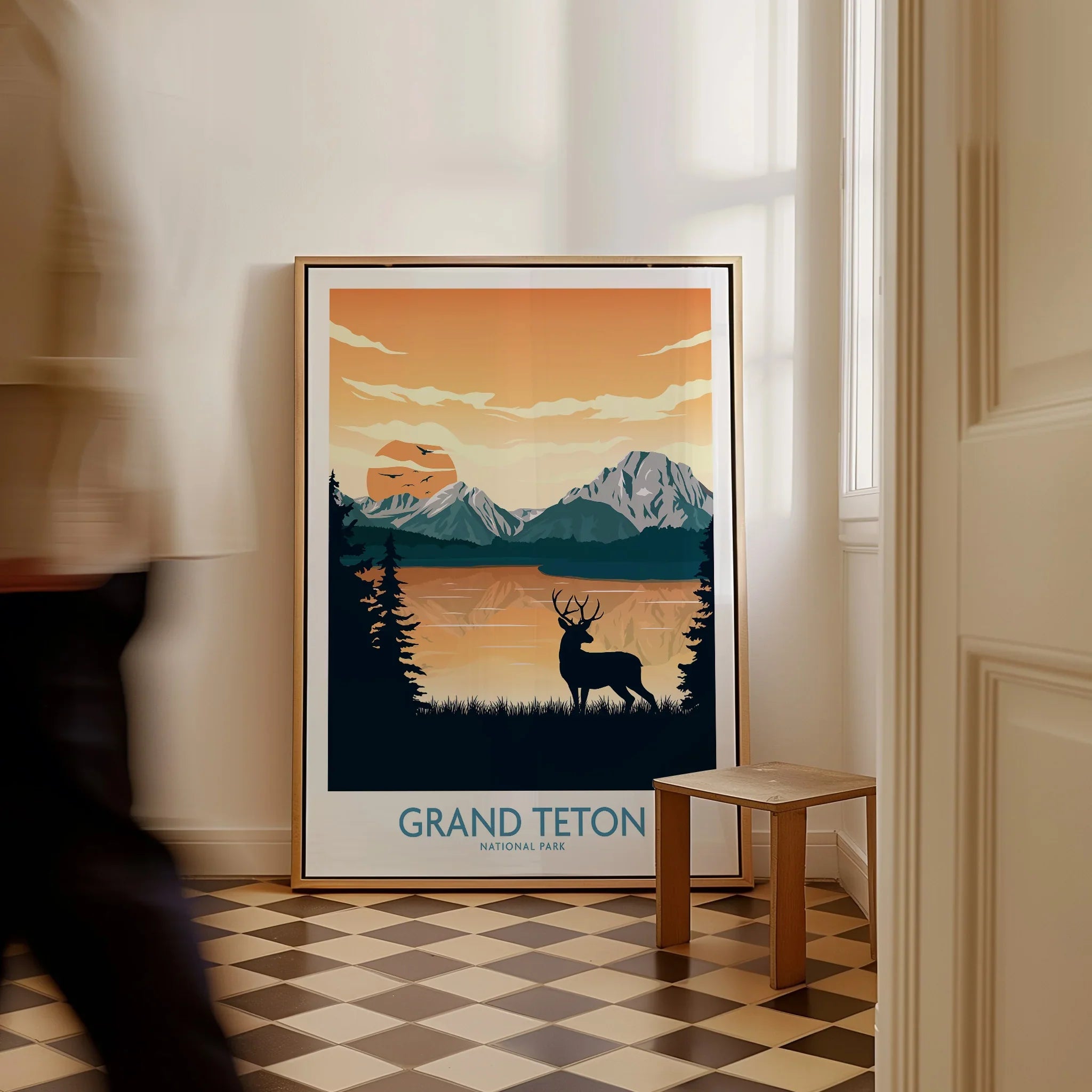 Framed Grand Teton National Park travel poster with mountains and deer on a hallway floor