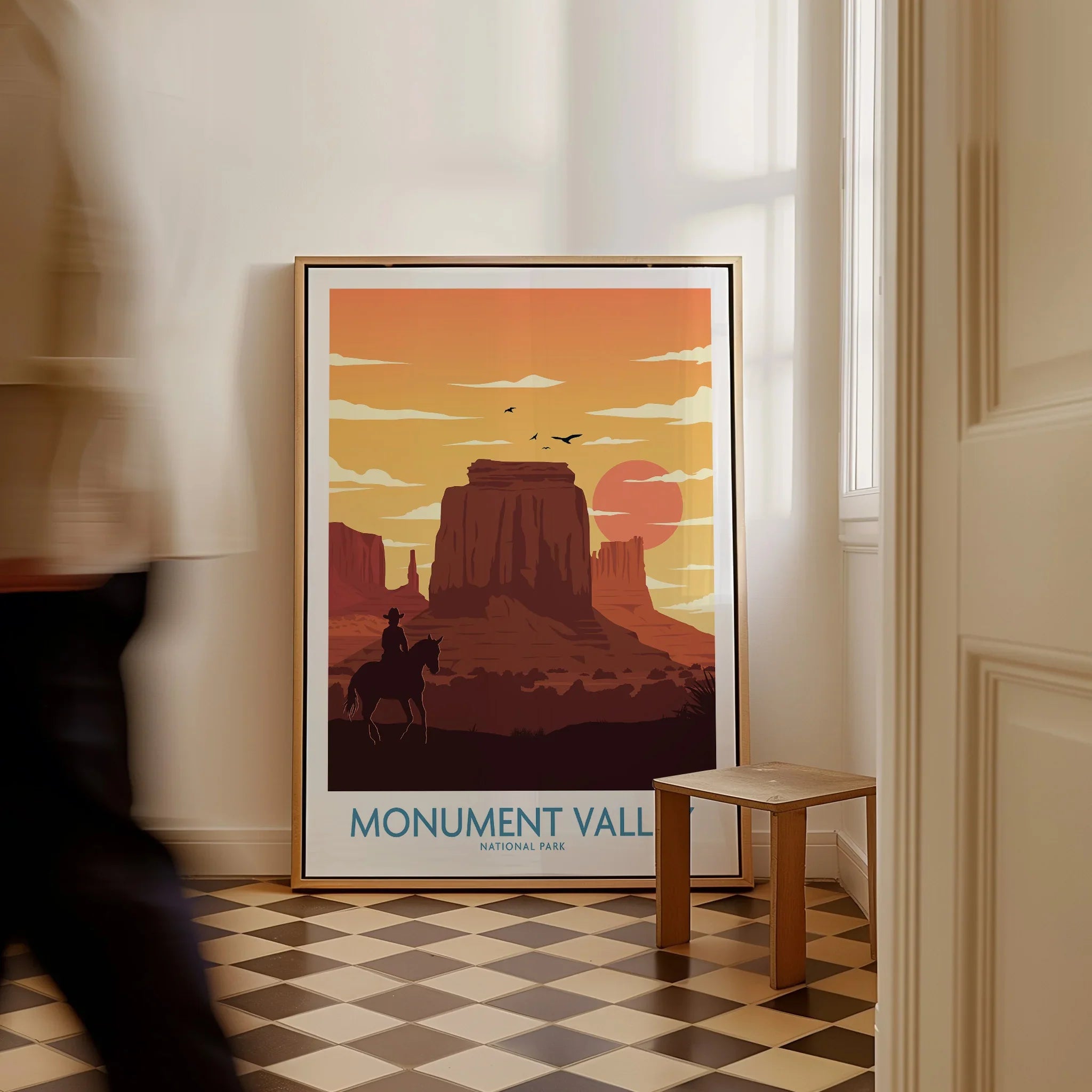 Framed Monument Valley National Park poster with sunset colors in a hallway, man walking past