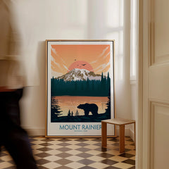 Framed Mount Rainier National Park travel poster with bear silhouette on floor, man walking past.
