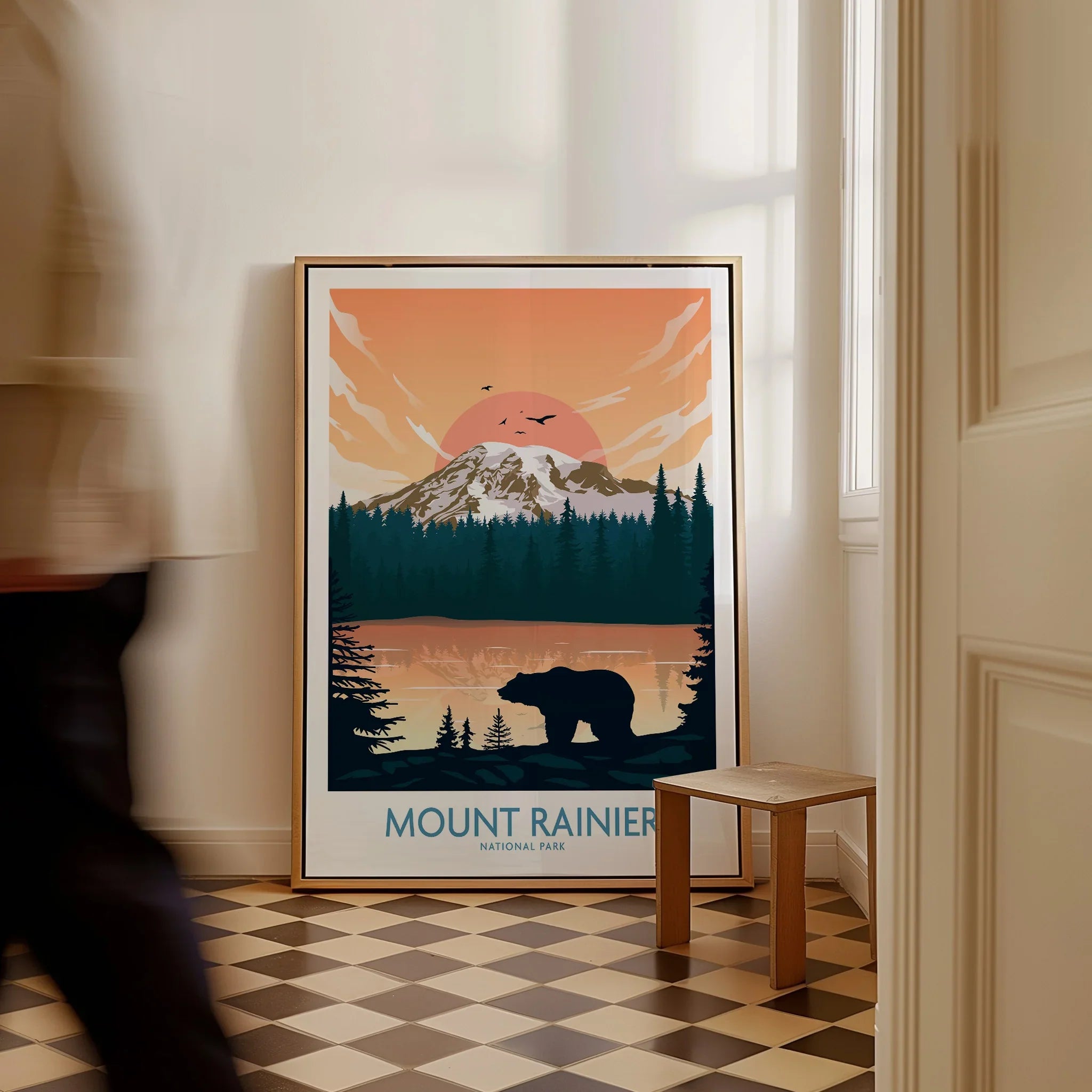 Framed Mount Rainier National Park travel poster with bear silhouette on floor, man walking past.