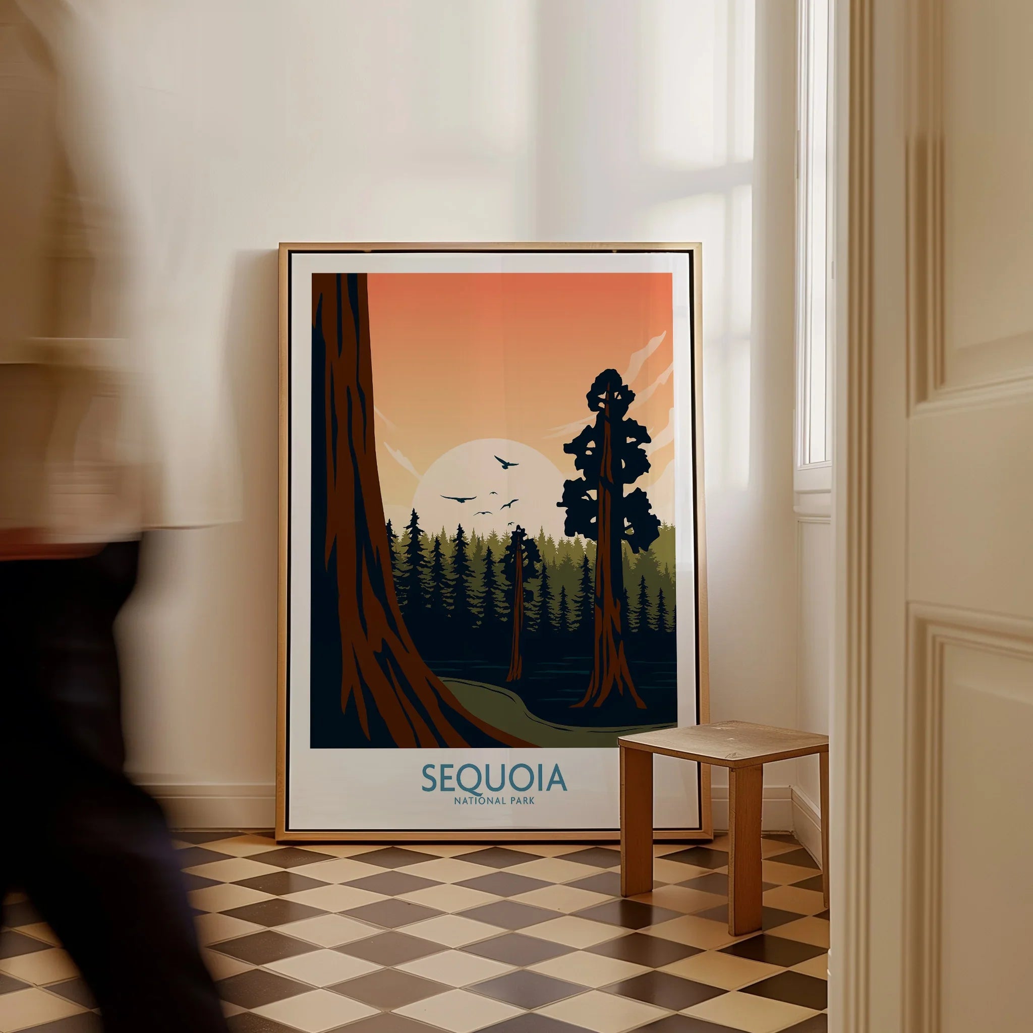 Framed Sequoia National Park poster on floor, with person walking past in bright hallway