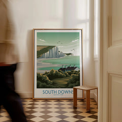 Framed South Downs National Park travel poster on floor in stylish hallway, man walking past.