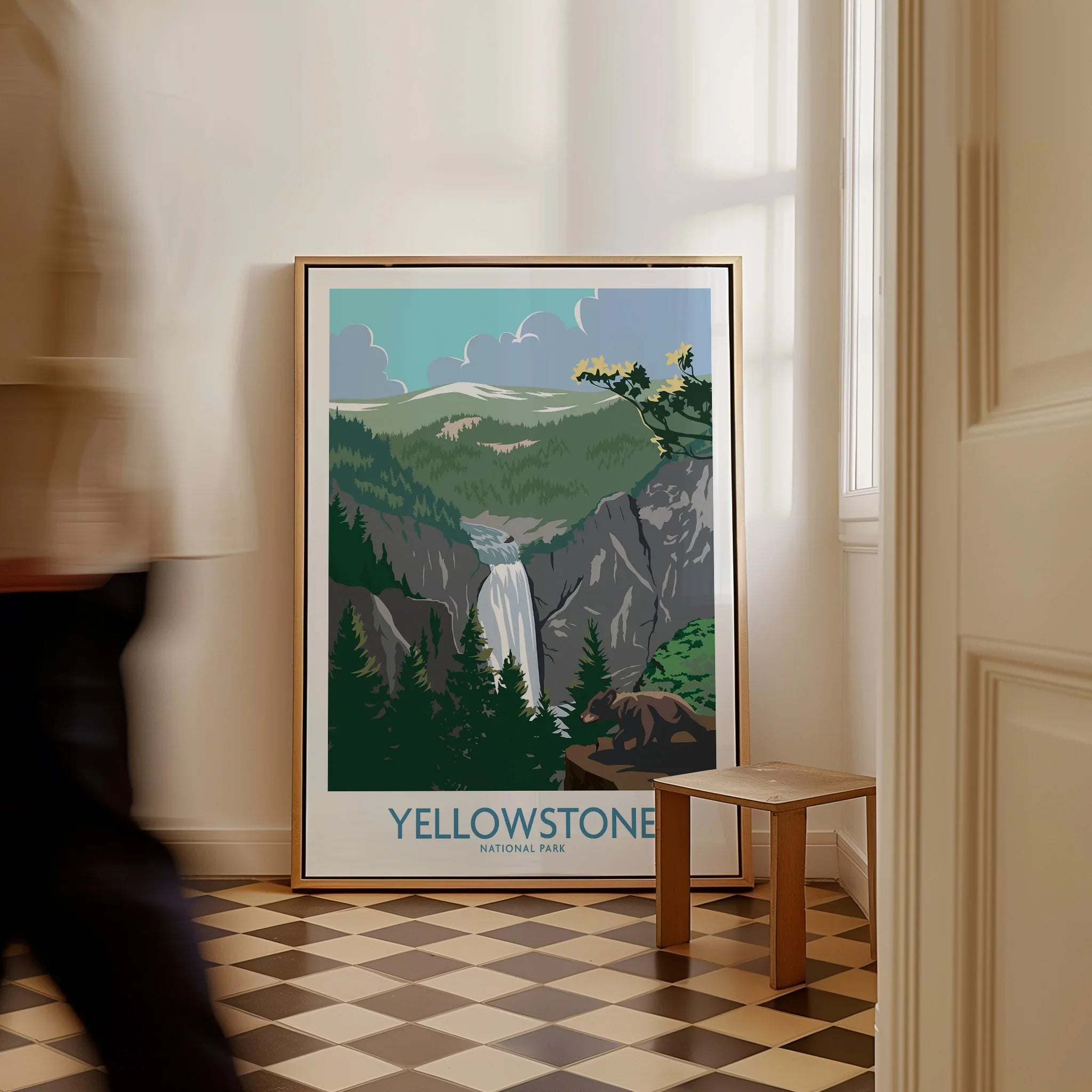 Framed Yellowstone National Park travel poster with waterfall art on floor, person walking by
