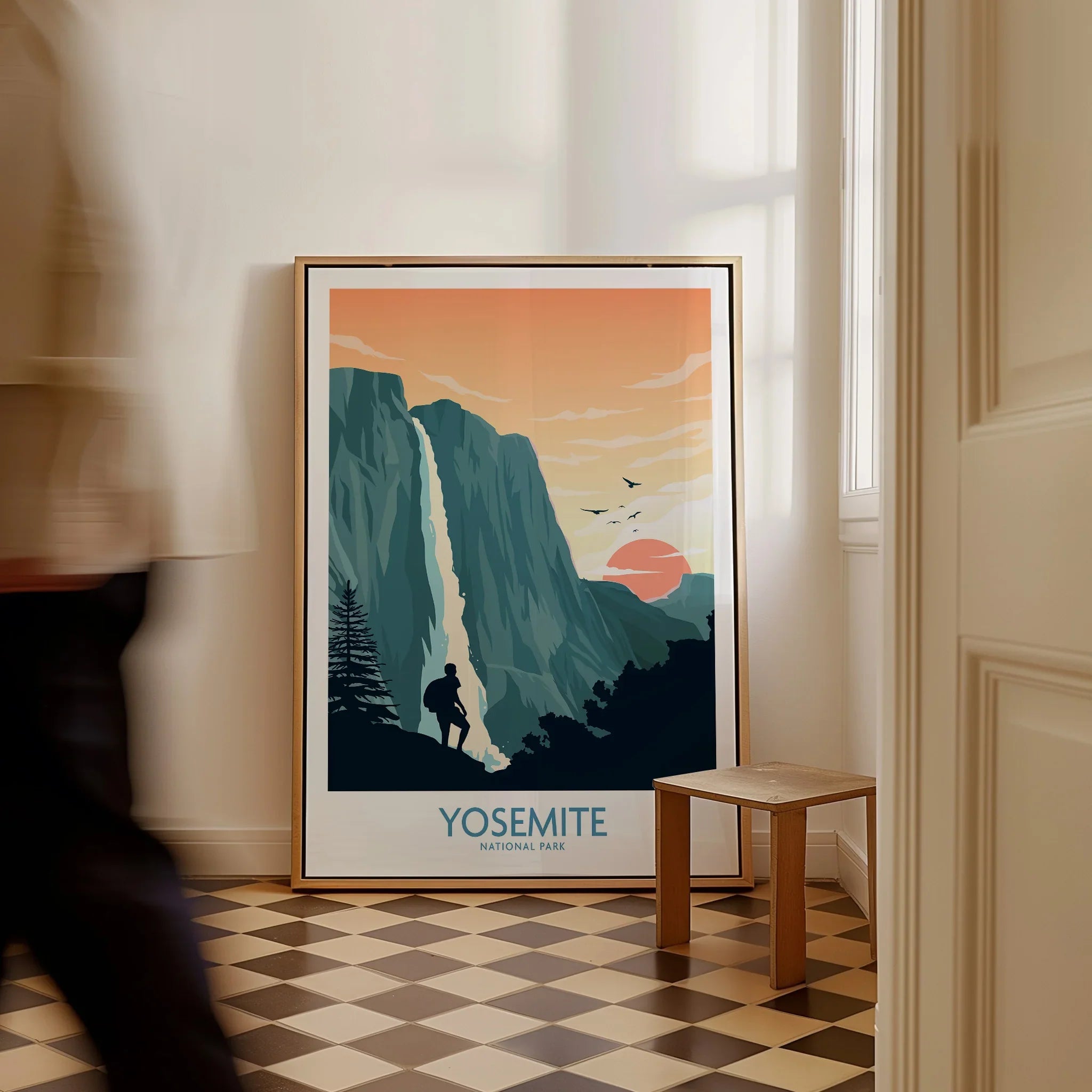 Framed Yosemite National Park travel poster with hiker and waterfall on floor in modern hallway