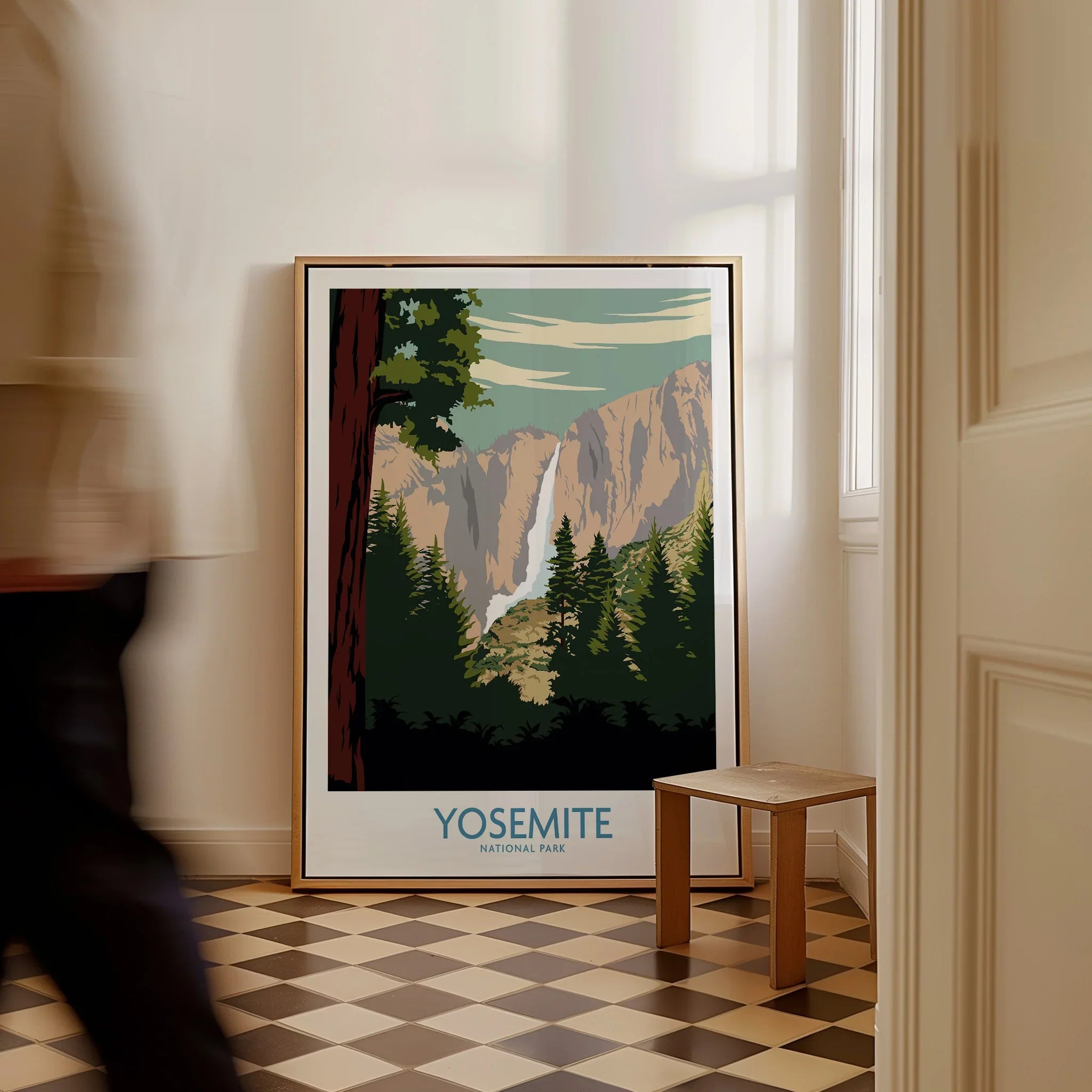 Framed Yosemite National Park travel poster with waterfall, placed on checkered floor indoors