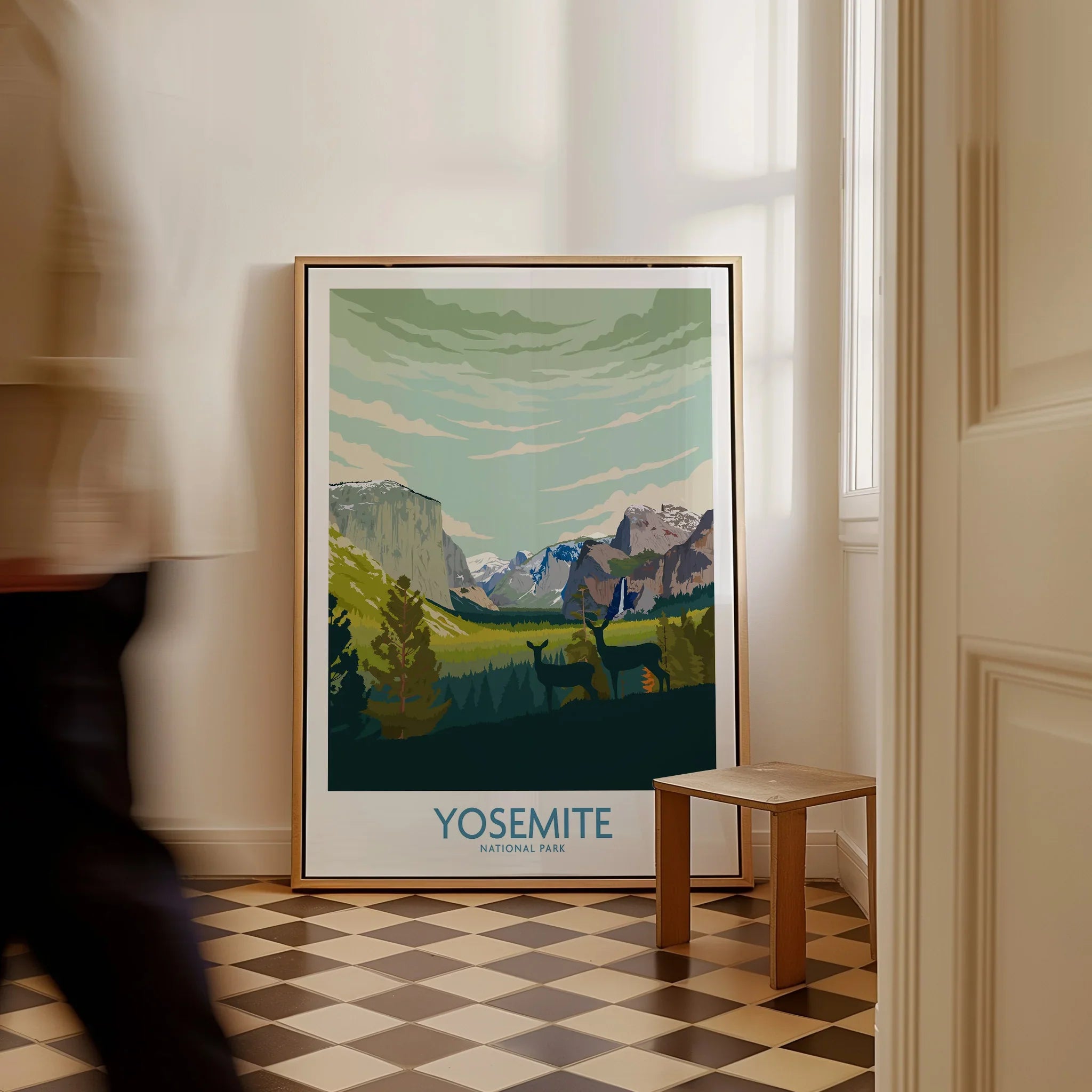 Framed Yosemite National Park art print on floor in bright hallway, man walking past