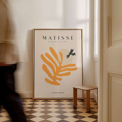 Matisse Art Prints - Orange Leaf Bird Silhouette Poster displayed in a modern interior setting with a brown and beige floor.