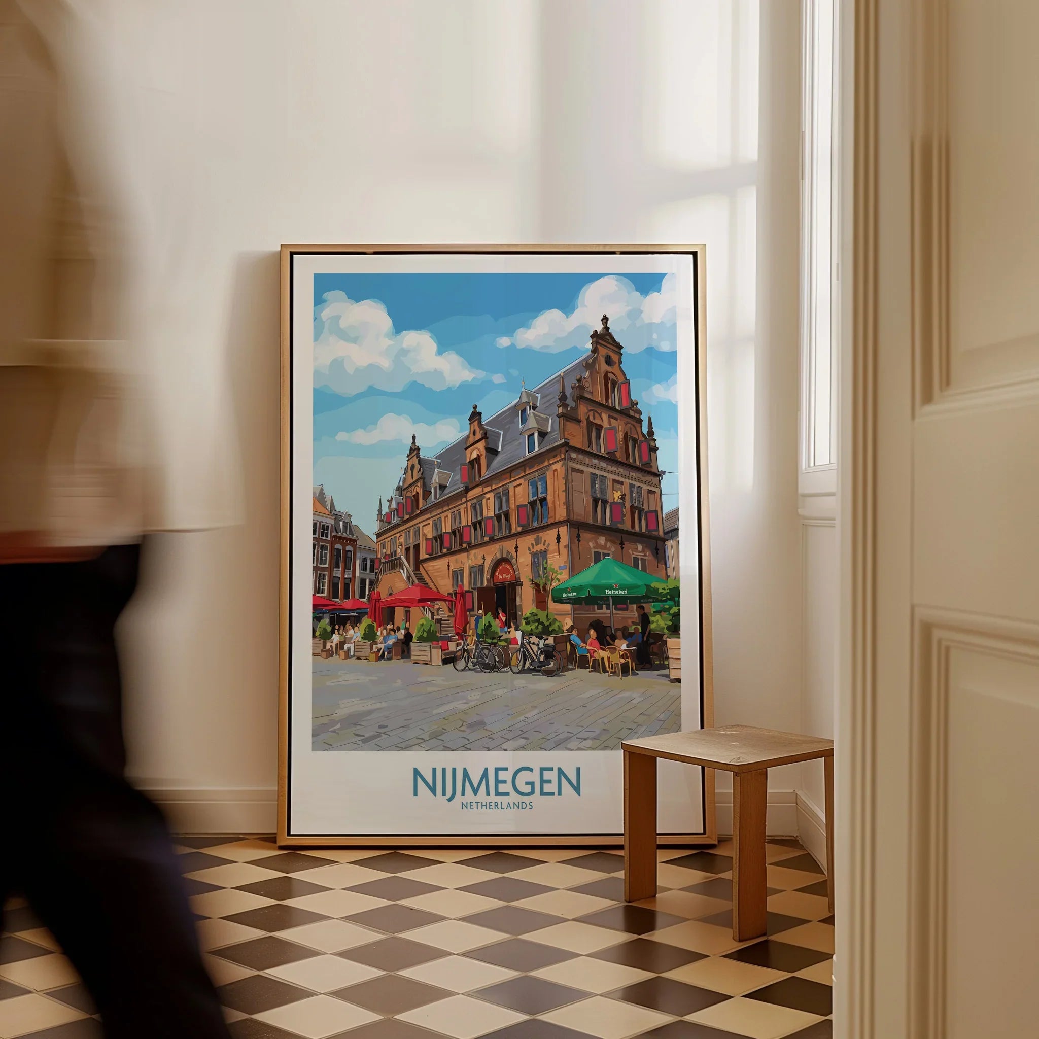 Framed Nijmegen Netherlands travel poster leaning on wall, man walking past in hallway