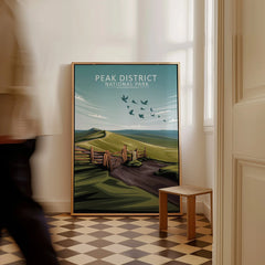 Framed Peak District National Park travel poster with landscape art on floor, man walking past