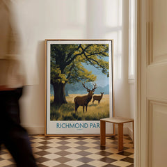 Framed Richmond Park travel poster with deer and tree, leaning on wall in modern hallway.