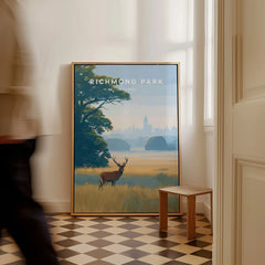 Framed Richmond Park wall art print with deer on floor in sunlit hallway, man walking past