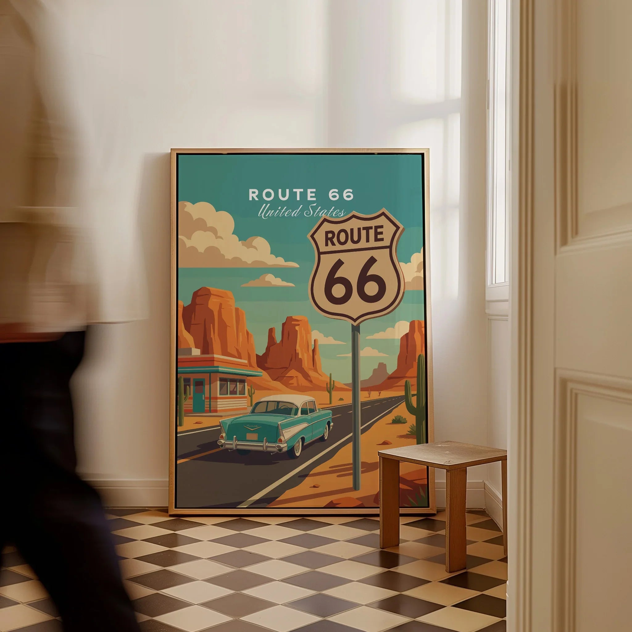 Framed Route 66 travel poster with vintage car and desert scene on floor in hallway