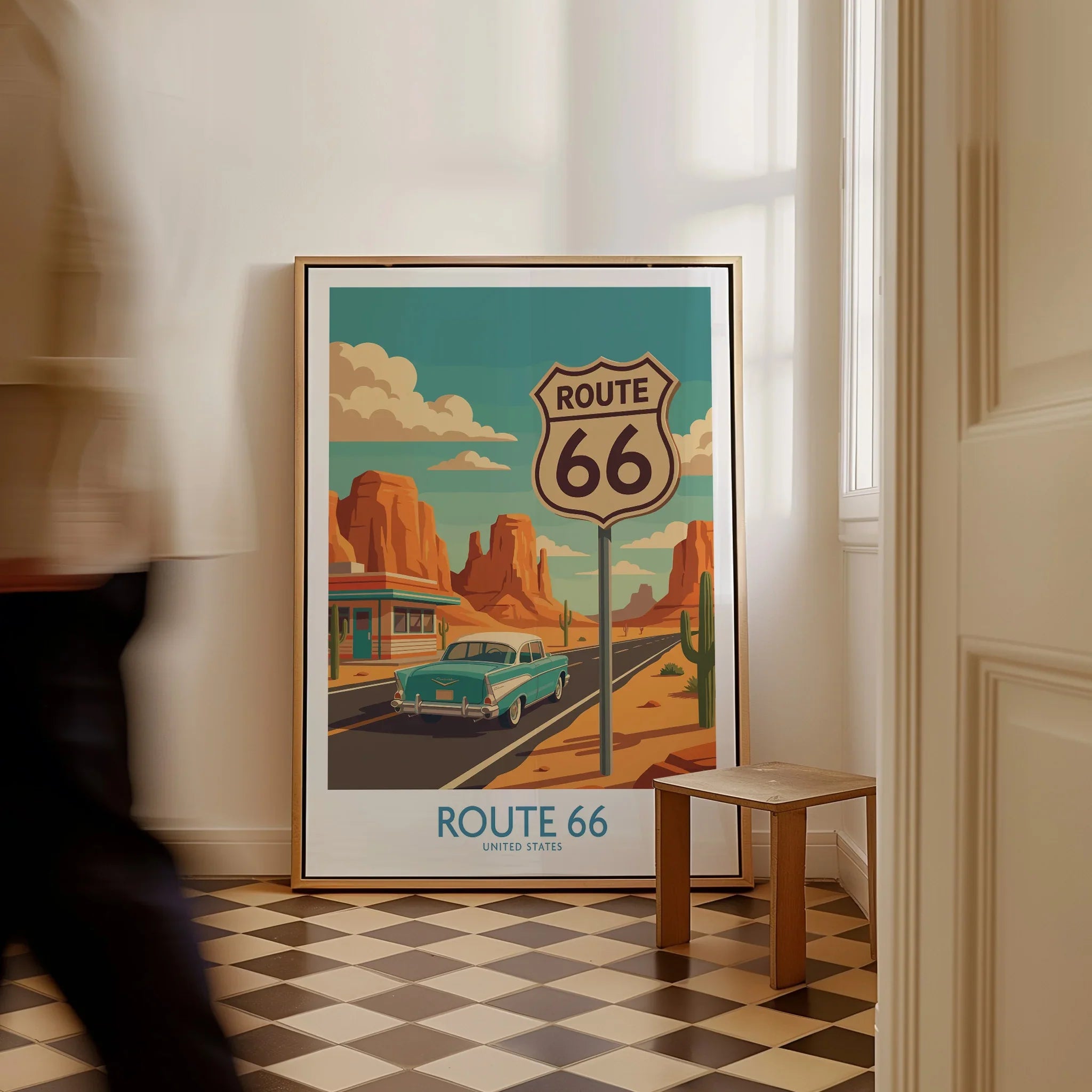 Framed Route 66 travel poster with vintage car and desert highway, leaning on a floor.