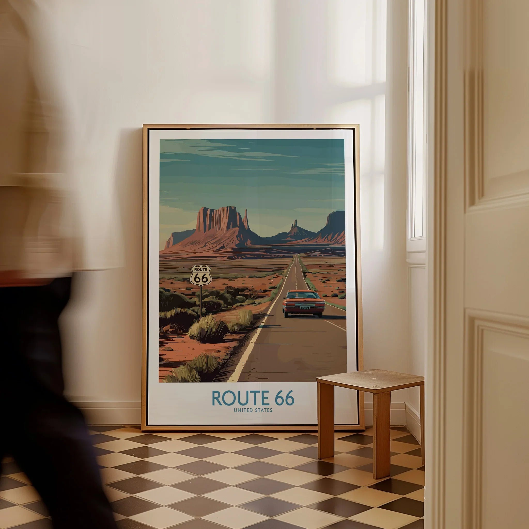 Framed Route 66 travel poster with desert landscape on floor in modern hallway