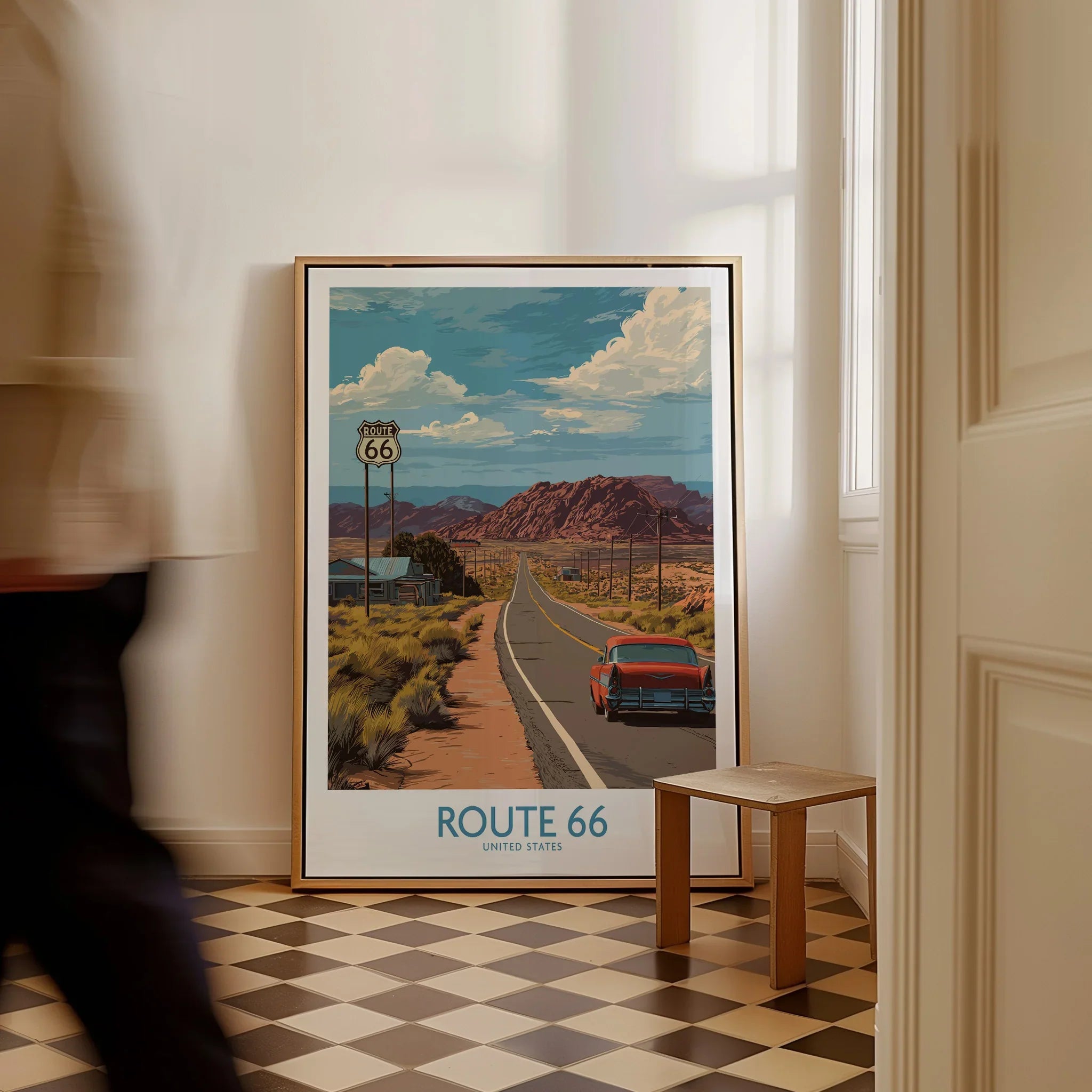 Framed Route 66 travel poster with vintage car, desert landscape, on a tiled floor indoors.