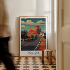 Framed Route 66 travel poster with desert landscape leaning on wall, man walking past.