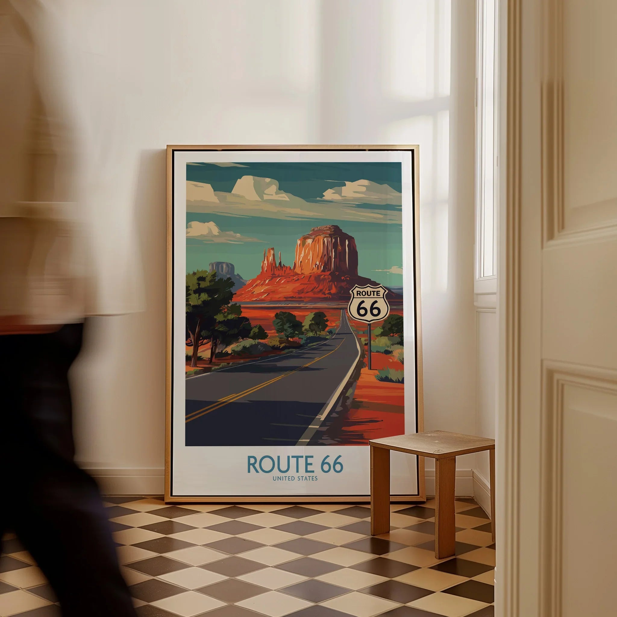 Framed Route 66 travel poster with desert landscape leaning on wall, man walking past.