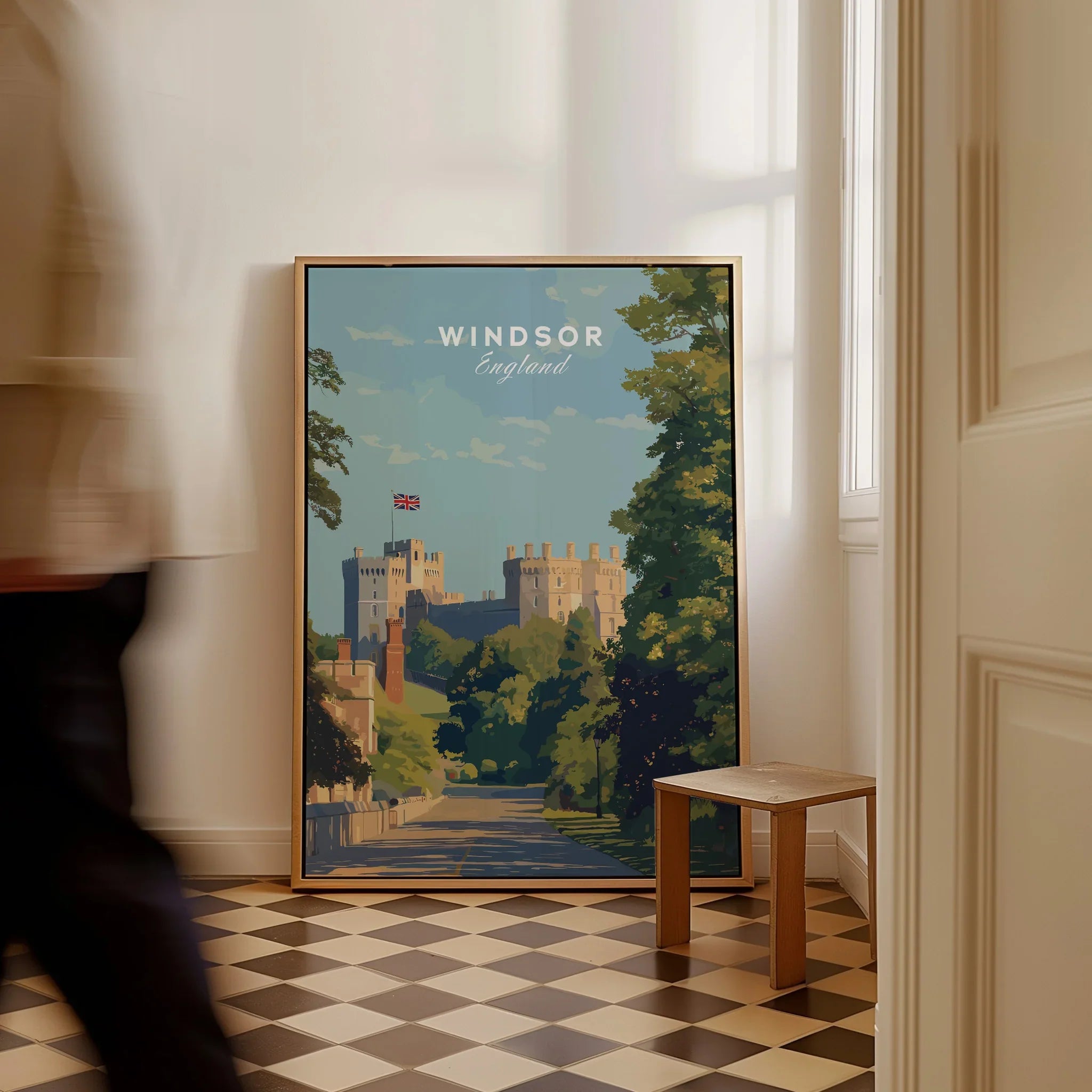 Framed Windsor England travel poster on floor in bright room, man walking past, checkered tiles