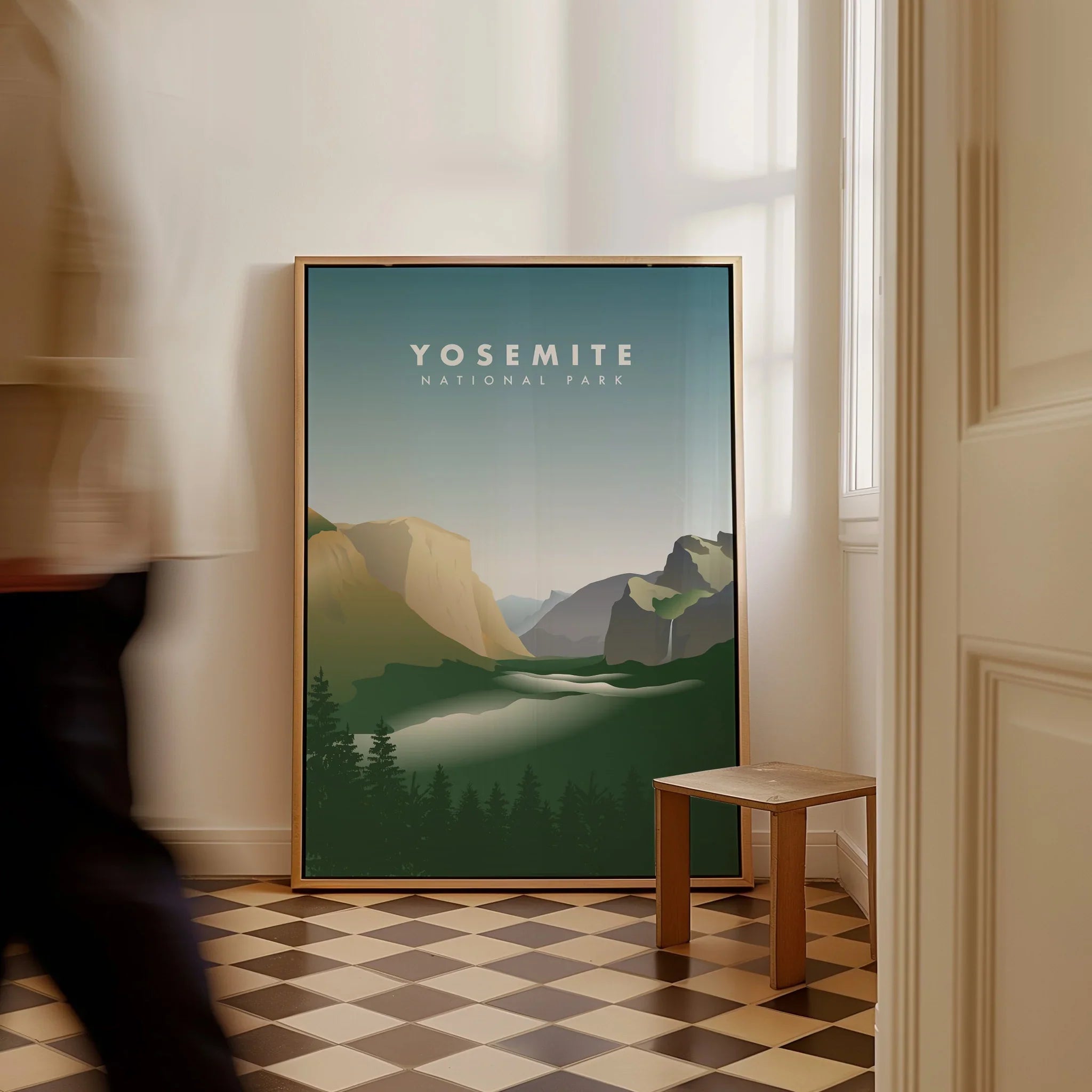 Framed Yosemite National Park print on floor in sunlit room, man walking past