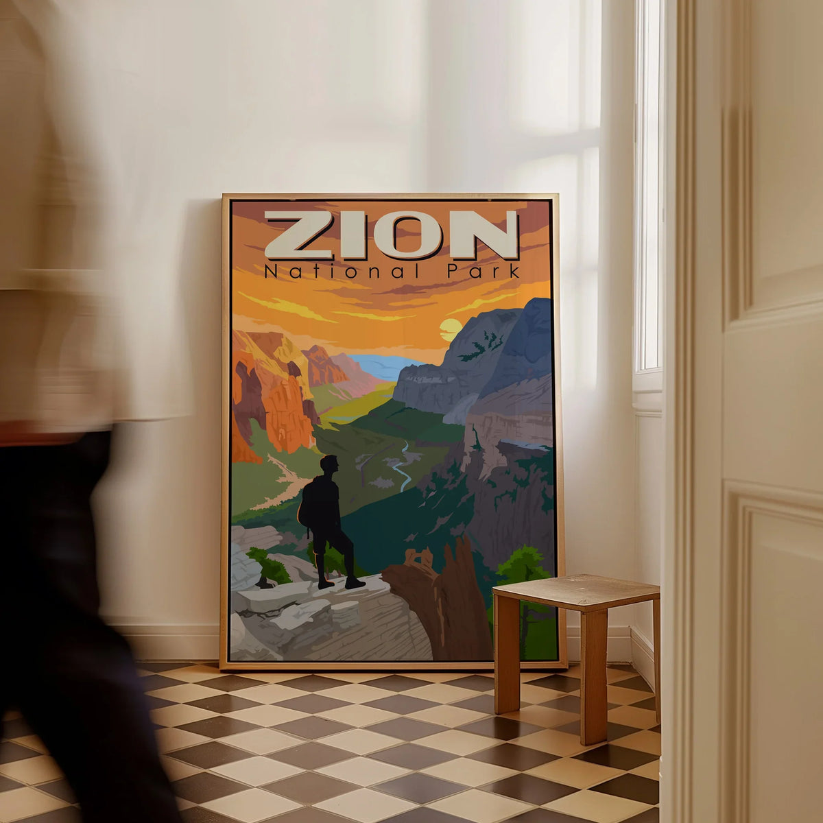 Framed Zion National Park travel poster on floor in bright hallway with man walking past