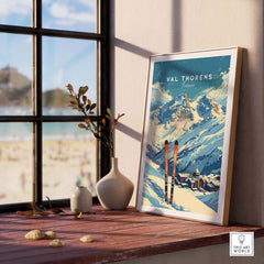 Val Thorens travel poster framed on a window sill, showcasing stunning mountain views and ski gear in a cozy setting.