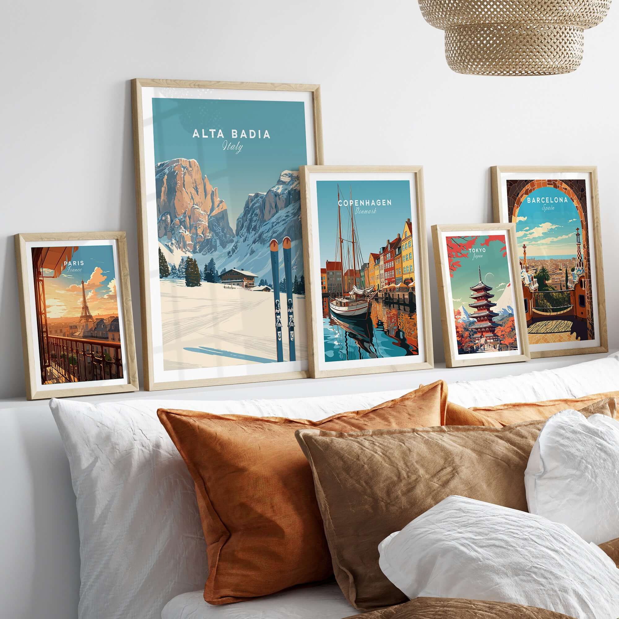 Framed Alta Badia Italy Ski Resort print among other travel posters on a sofa, showcasing alpine beauty and adventure.