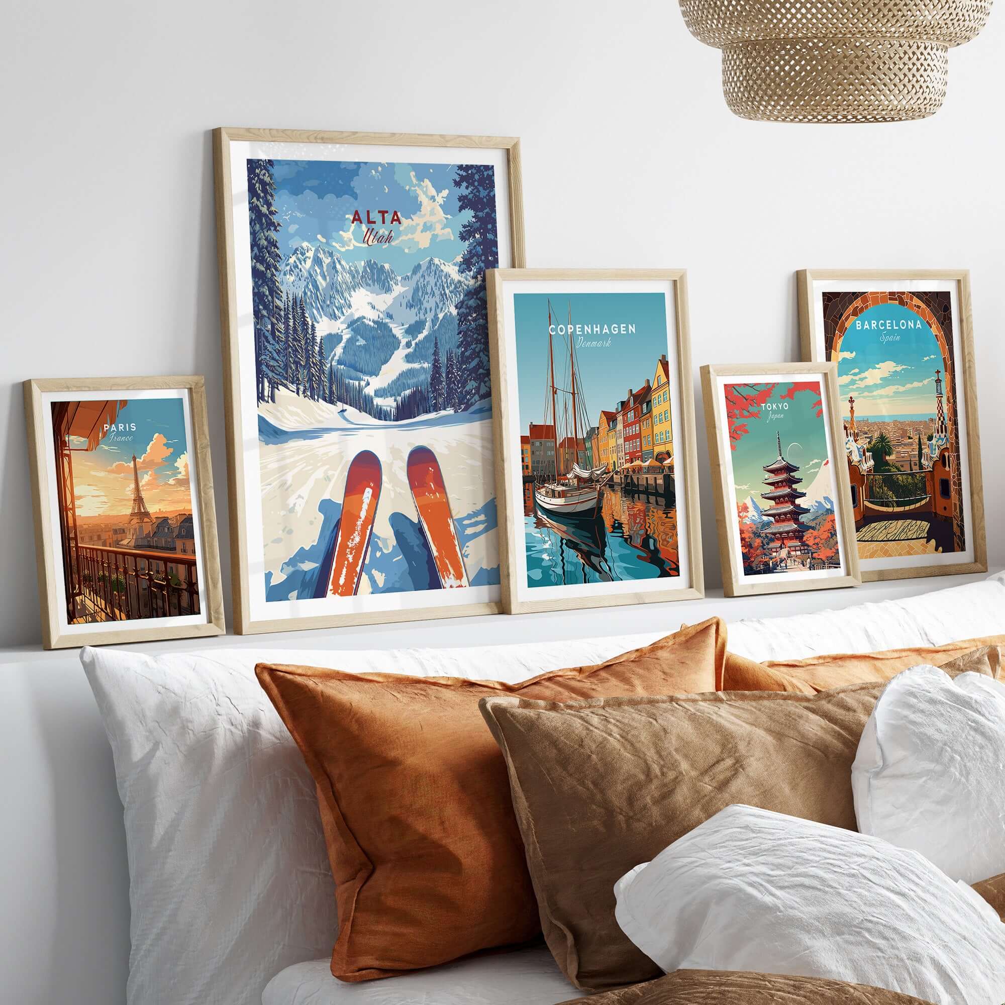 Gallery of framed travel prints including Alta Utah ski view, Copenhagen, and Barcelona on a cozy couch.