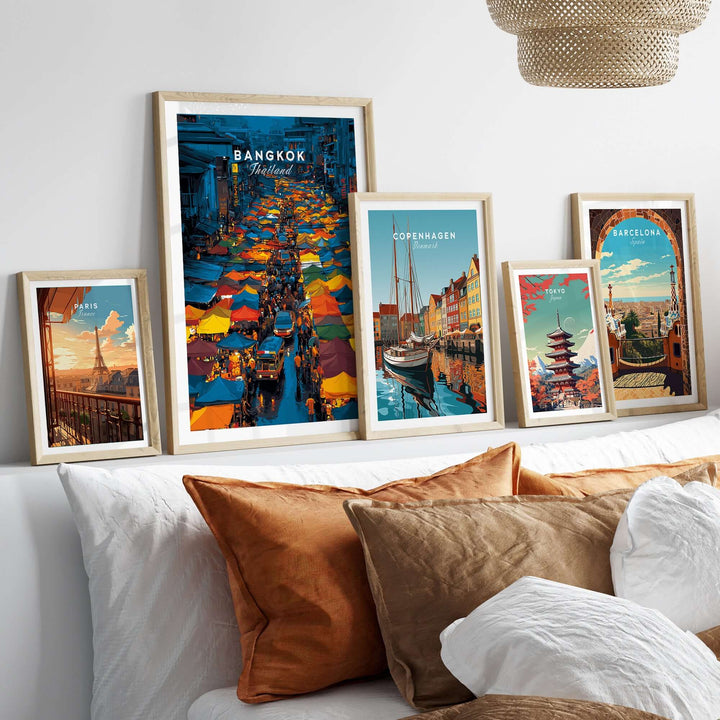Gallery of vibrant travel posters including Bangkok night market, Copenhagen, and Barcelona on a cozy sofa.