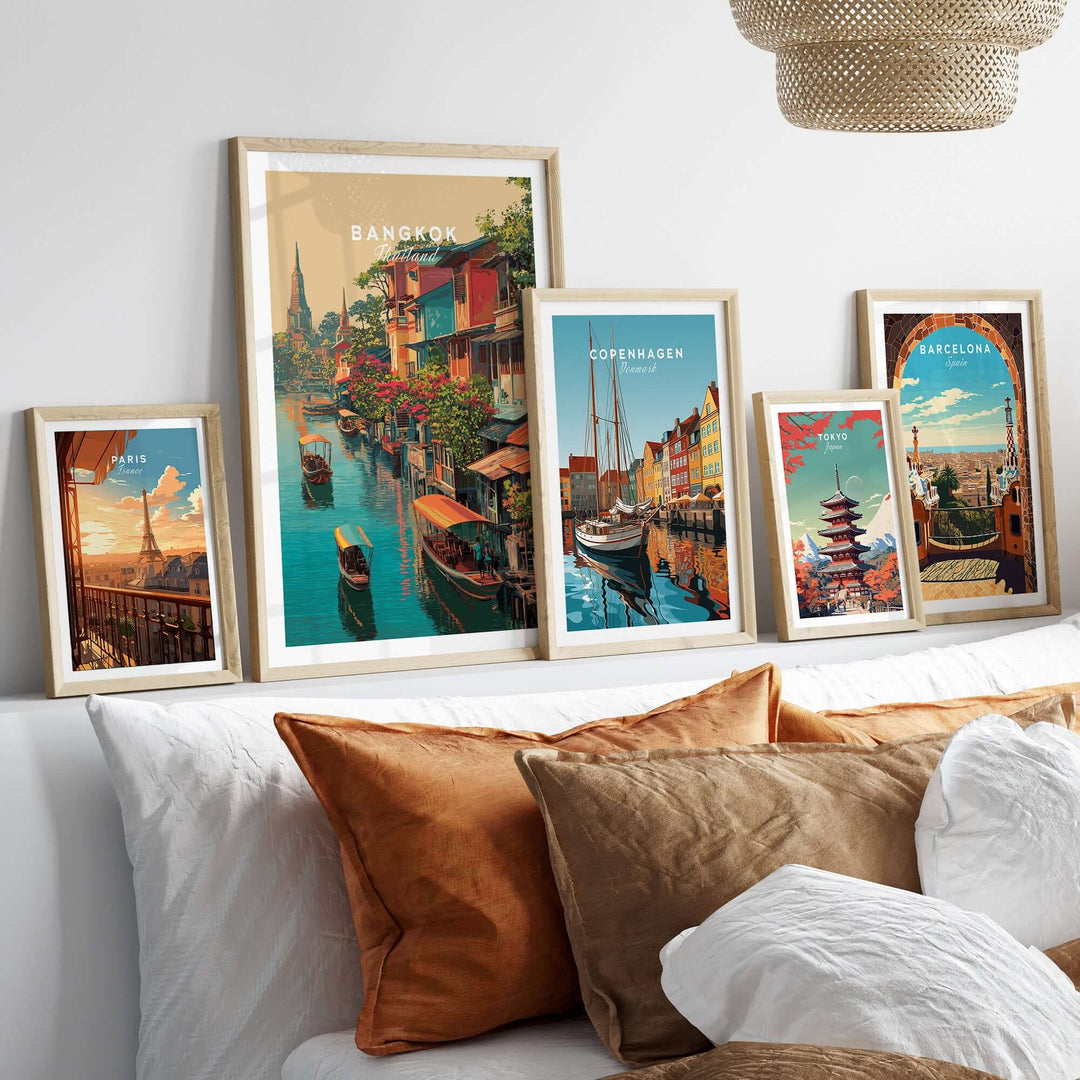 Framed wall art prints of Bangkok, Copenhagen, and Barcelona above a stylish sofa, showcasing vibrant cityscapes.