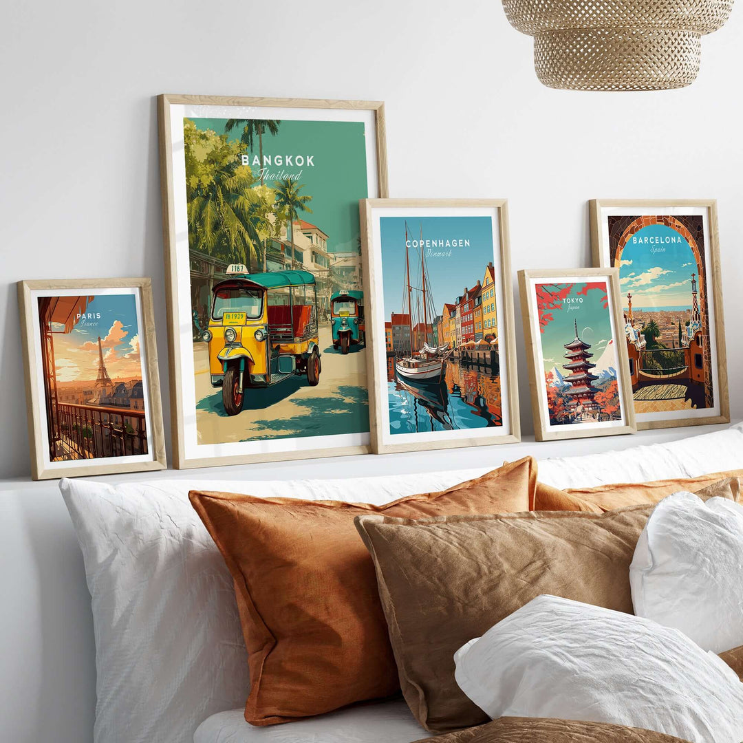 Bangkok tuk tuk city street poster displayed among framed travel art prints on a cozy bed.