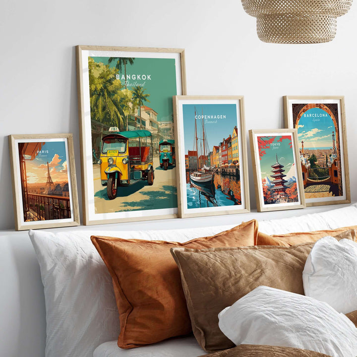Bangkok tuk tuk city street poster displayed among framed travel art prints on a cozy bed.